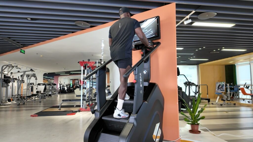 Usuario entrenando en una escaladora STEPR en la zona de cardio de un gimnasio comercial