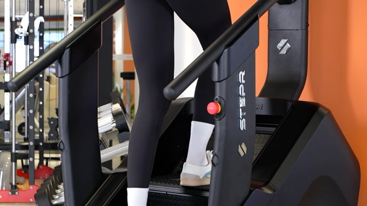 Usuaria subiendo escalones en una escaladora STEPR dentro de un gimnasio